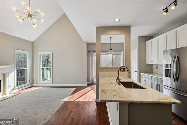 kitchen with light stone countertops, a sink, stainless steel fridge with ice dispenser, white cabinetry, and dark wood-type flooring