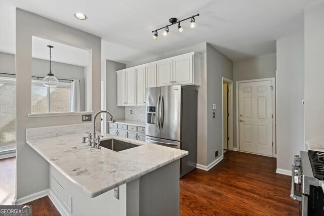 kitchen with a peninsula, stainless steel refrigerator with ice dispenser, white cabinets, light stone counters, and a sink