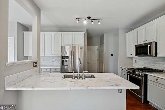 kitchen featuring light stone counters, a sink, decorative backsplash, and appliances with stainless steel finishes