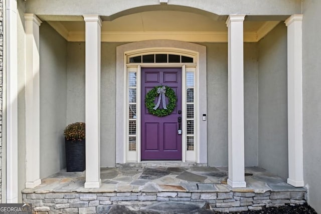 view of exterior entry featuring a porch and stucco siding