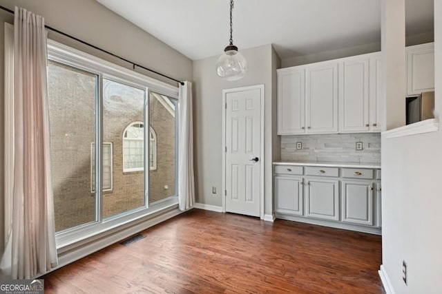 unfurnished dining area featuring baseboards, dark wood finished floors, and visible vents