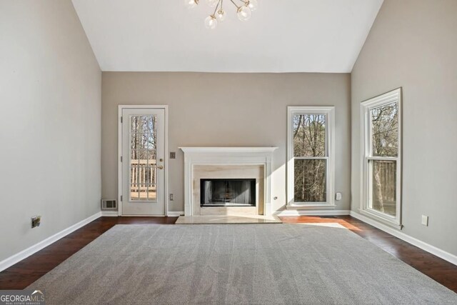 unfurnished living room with baseboards, a notable chandelier, vaulted ceiling, and a fireplace