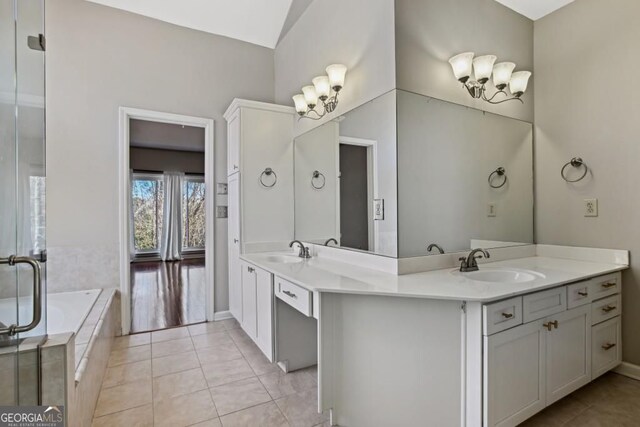 bathroom with a sink, tile patterned floors, double vanity, and a relaxing tiled tub
