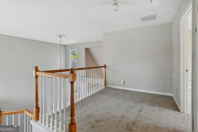 hallway with carpet floors, baseboards, visible vents, and an upstairs landing