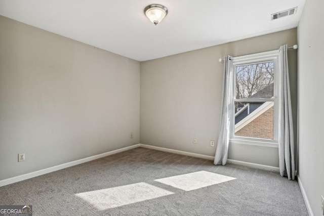 spare room with carpet floors, baseboards, and visible vents