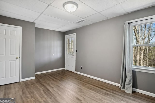 interior space with baseboards, a paneled ceiling, and wood finished floors