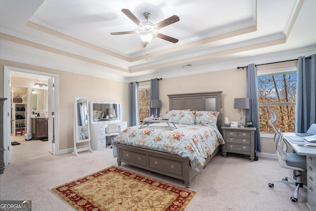 bedroom featuring crown molding, ceiling fan, light colored carpet, a tray ceiling, and ensuite bath