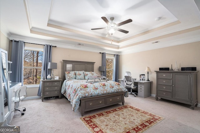 bedroom featuring ceiling fan, light colored carpet, crown molding, and a tray ceiling