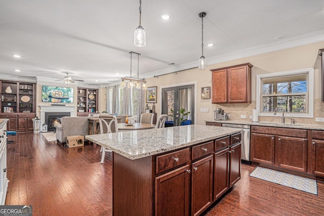 kitchen with decorative light fixtures, sink, backsplash, and a center island