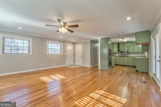 unfurnished living room featuring ceiling fan, sink, ornamental molding, and light wood-type flooring