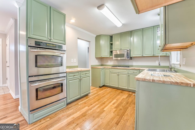 kitchen featuring sink, stainless steel appliances, ornamental molding, and green cabinetry