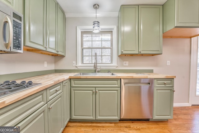 kitchen with appliances with stainless steel finishes, sink, hanging light fixtures, butcher block countertops, and green cabinets