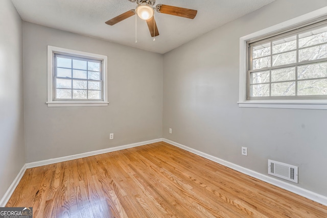 empty room with light hardwood / wood-style floors, a wealth of natural light, and ceiling fan