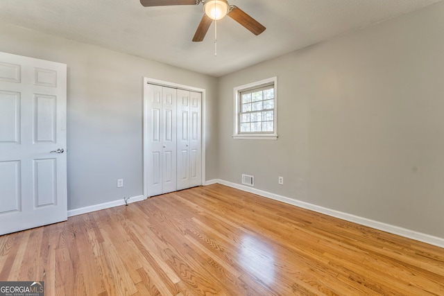 unfurnished bedroom with ceiling fan, a closet, and light wood-type flooring