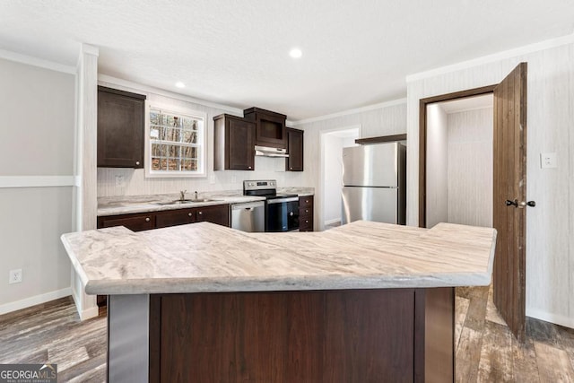 kitchen with a center island, sink, crown molding, dark brown cabinetry, and appliances with stainless steel finishes