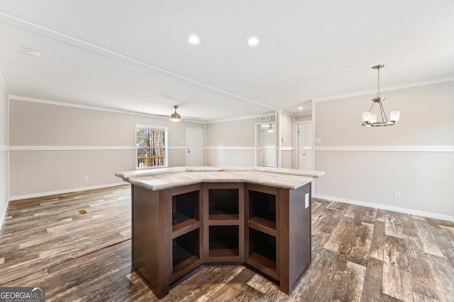 kitchen with ceiling fan with notable chandelier, a center island, decorative light fixtures, dark hardwood / wood-style flooring, and crown molding