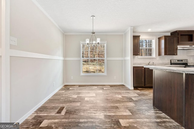 kitchen with sink, dark brown cabinets, stainless steel range with electric cooktop, and crown molding