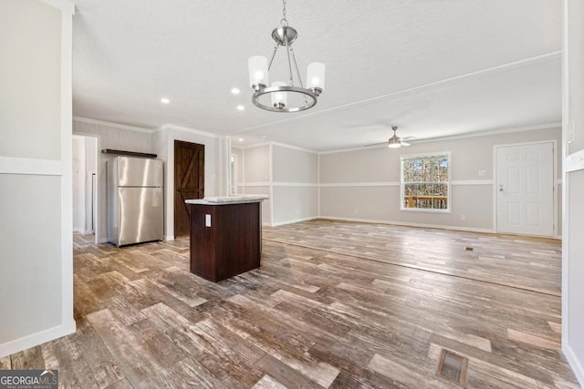 kitchen with decorative light fixtures, light hardwood / wood-style floors, stainless steel refrigerator, ornamental molding, and dark brown cabinets