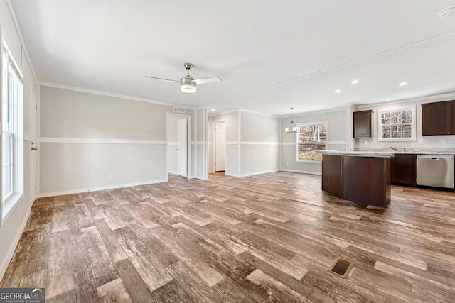 unfurnished living room featuring ceiling fan with notable chandelier, crown molding, and light wood-type flooring