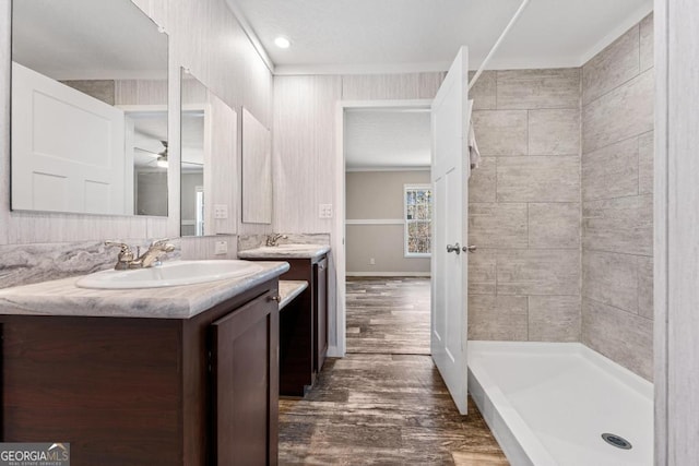 bathroom with a shower, hardwood / wood-style floors, ceiling fan, ornamental molding, and vanity