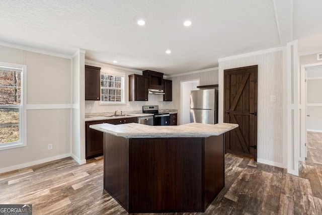 kitchen featuring dark brown cabinetry, stainless steel appliances, crown molding, and a kitchen island