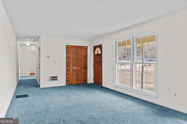 carpeted spare room with a textured ceiling