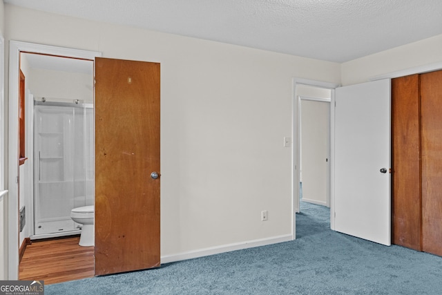 unfurnished bedroom with ensuite bathroom, carpet, a textured ceiling, and a closet