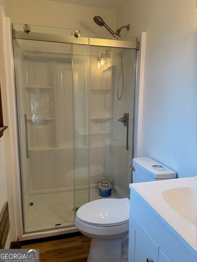 bathroom with vanity, hardwood / wood-style floors, a shower with door, and toilet