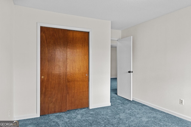 unfurnished bedroom featuring a closet, a textured ceiling, and dark colored carpet