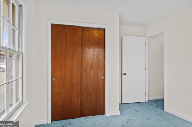 unfurnished bedroom with light carpet and a closet