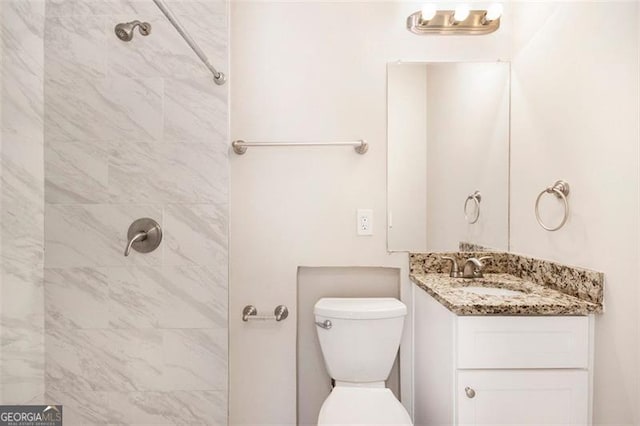 bathroom featuring toilet, vanity, and tiled shower