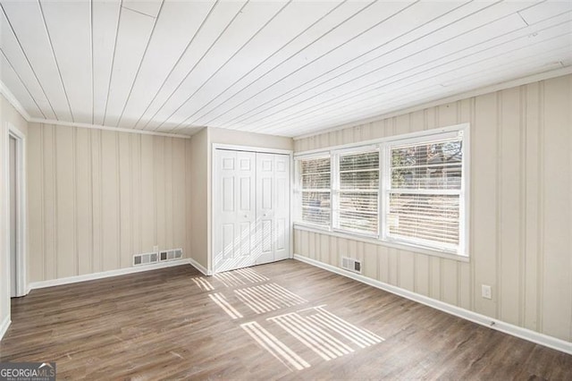 unfurnished bedroom featuring a closet, wood ceiling, hardwood / wood-style floors, and crown molding