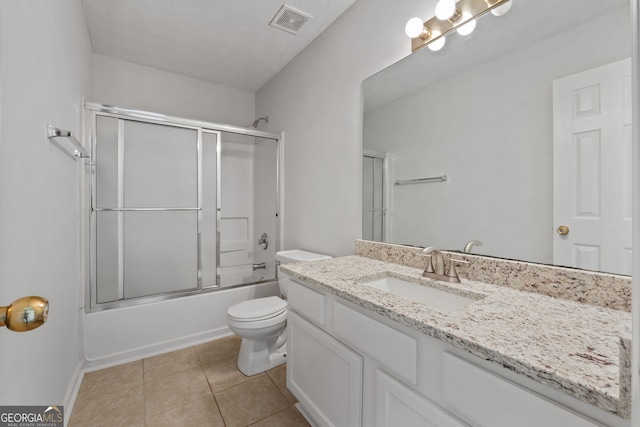 full bathroom featuring toilet, bath / shower combo with glass door, tile patterned floors, a textured ceiling, and vanity