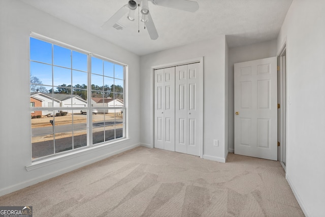 unfurnished bedroom featuring ceiling fan, a closet, and light carpet