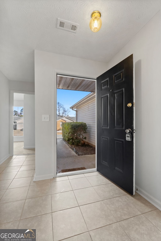 foyer featuring a textured ceiling and light tile patterned floors