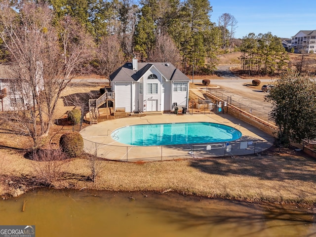 view of pool featuring a water view, a patio, and an outbuilding