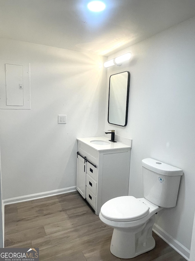 bathroom with vanity, hardwood / wood-style floors, electric panel, and toilet