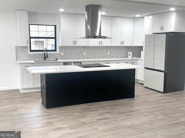 kitchen featuring a kitchen island, island range hood, refrigerator, white cabinetry, and sink