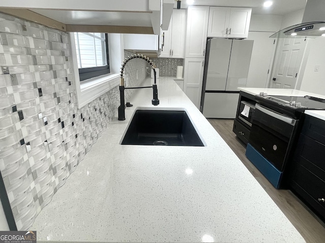 kitchen with sink, white cabinetry, island range hood, stainless steel refrigerator, and range with electric cooktop