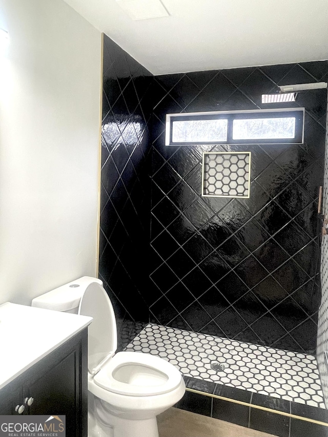 bathroom featuring vanity, a wealth of natural light, a tile shower, and toilet