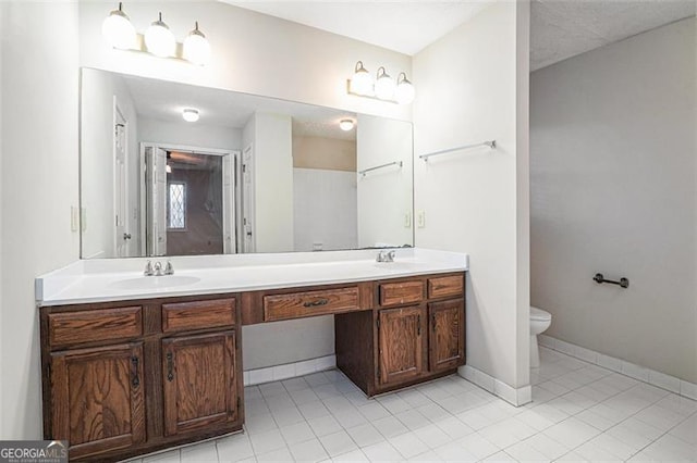 bathroom with toilet, vanity, and tile patterned flooring