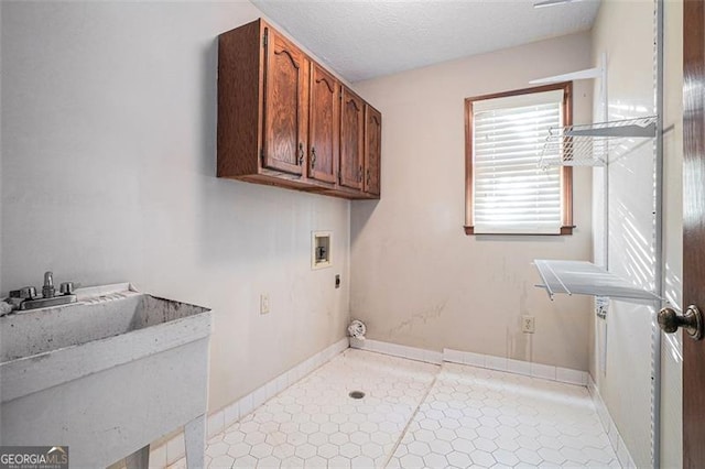 clothes washing area featuring hookup for an electric dryer, a textured ceiling, washer hookup, cabinets, and sink