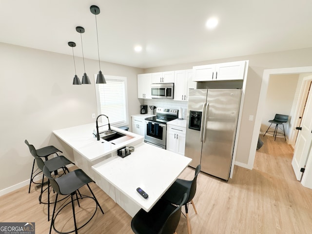 kitchen with decorative backsplash, sink, white cabinetry, hanging light fixtures, and appliances with stainless steel finishes