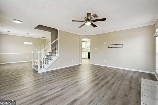 unfurnished living room featuring ceiling fan with notable chandelier, hardwood / wood-style floors, and ornamental molding