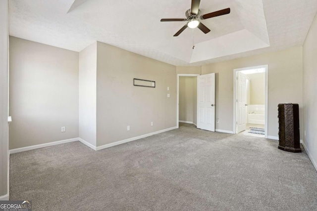 unfurnished bedroom featuring ceiling fan, carpet, a raised ceiling, connected bathroom, and a textured ceiling