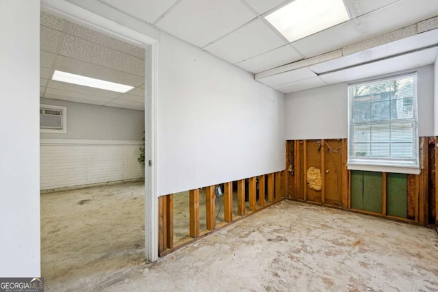 unfurnished room with brick wall, a paneled ceiling, and a wall mounted AC