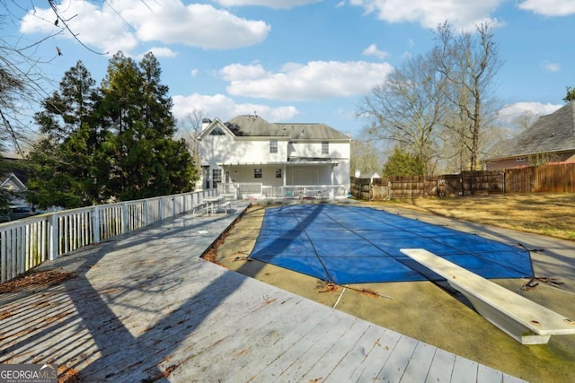 view of swimming pool with a patio area, a diving board, and a wooden deck