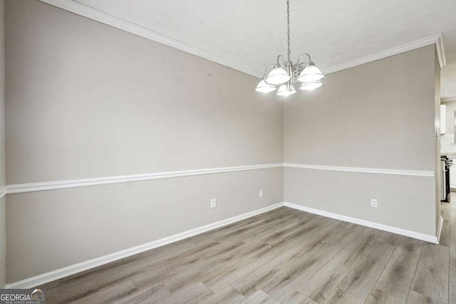 unfurnished room with light wood-type flooring, a chandelier, and ornamental molding