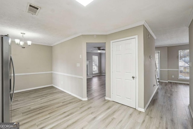 spare room featuring light wood-type flooring, a textured ceiling, crown molding, and plenty of natural light