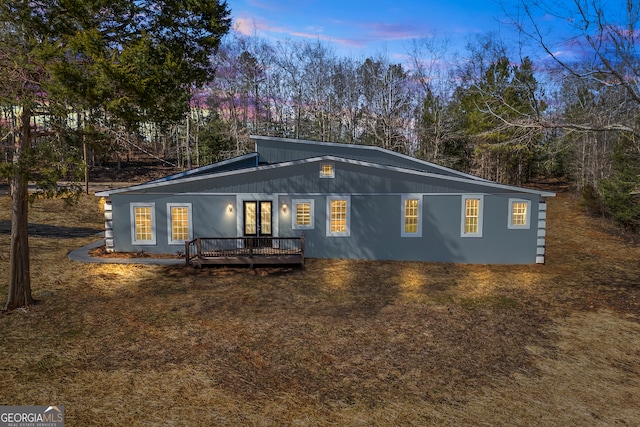 back house at dusk featuring a wooden deck